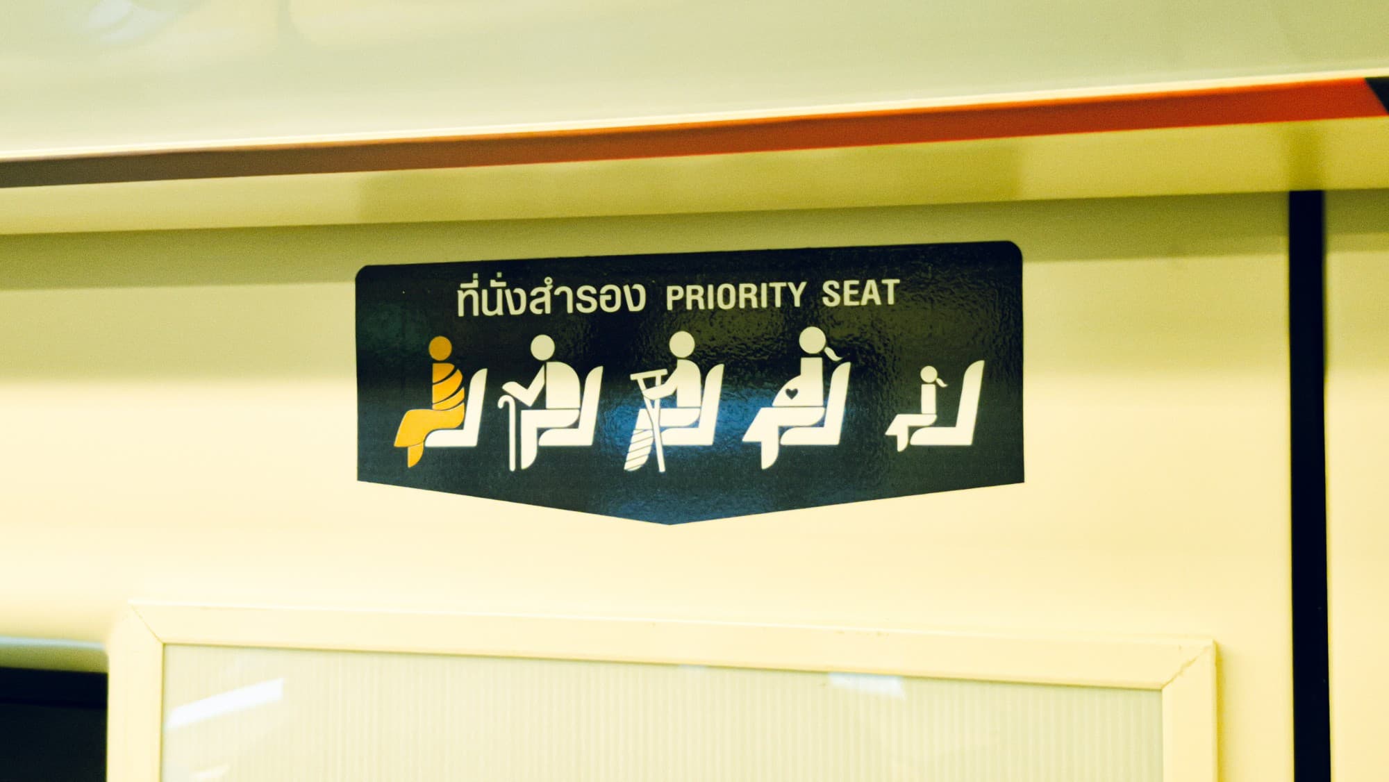A "Priority seat" sign in Thai and English on a train wall