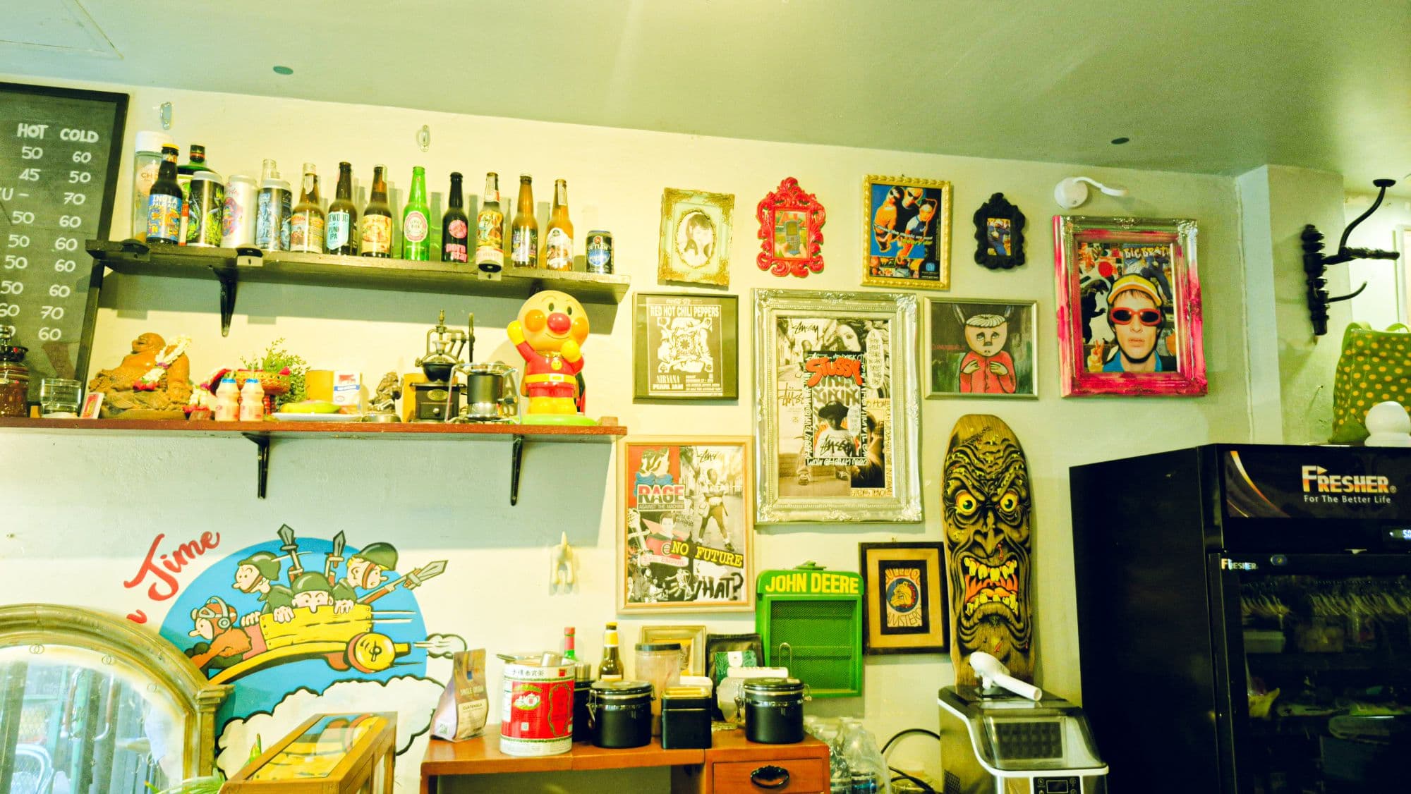 A cafe wall of framed posters, bottles on shelves and a toy figure